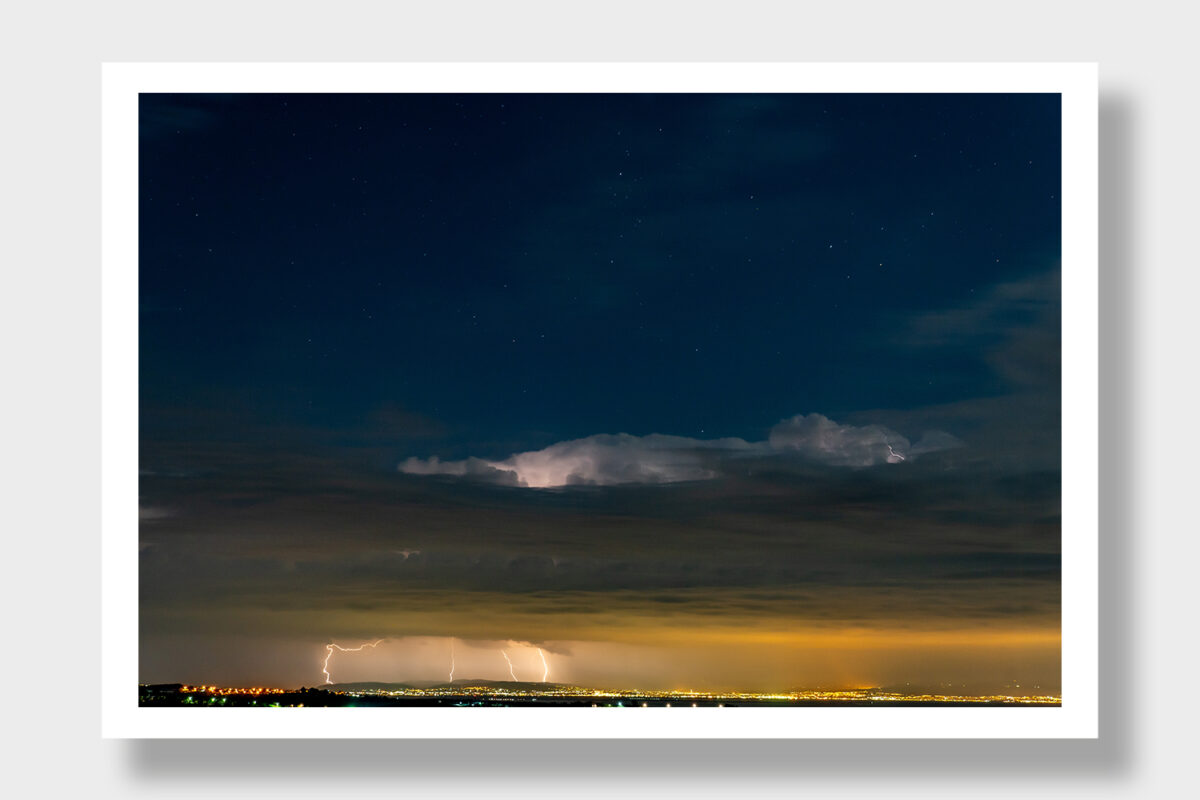 A panoramic view from Greece towards Thessaloniki and Chalkidiki - a dramatic seascape with storm clouds, lightning, and a clear starry sky.