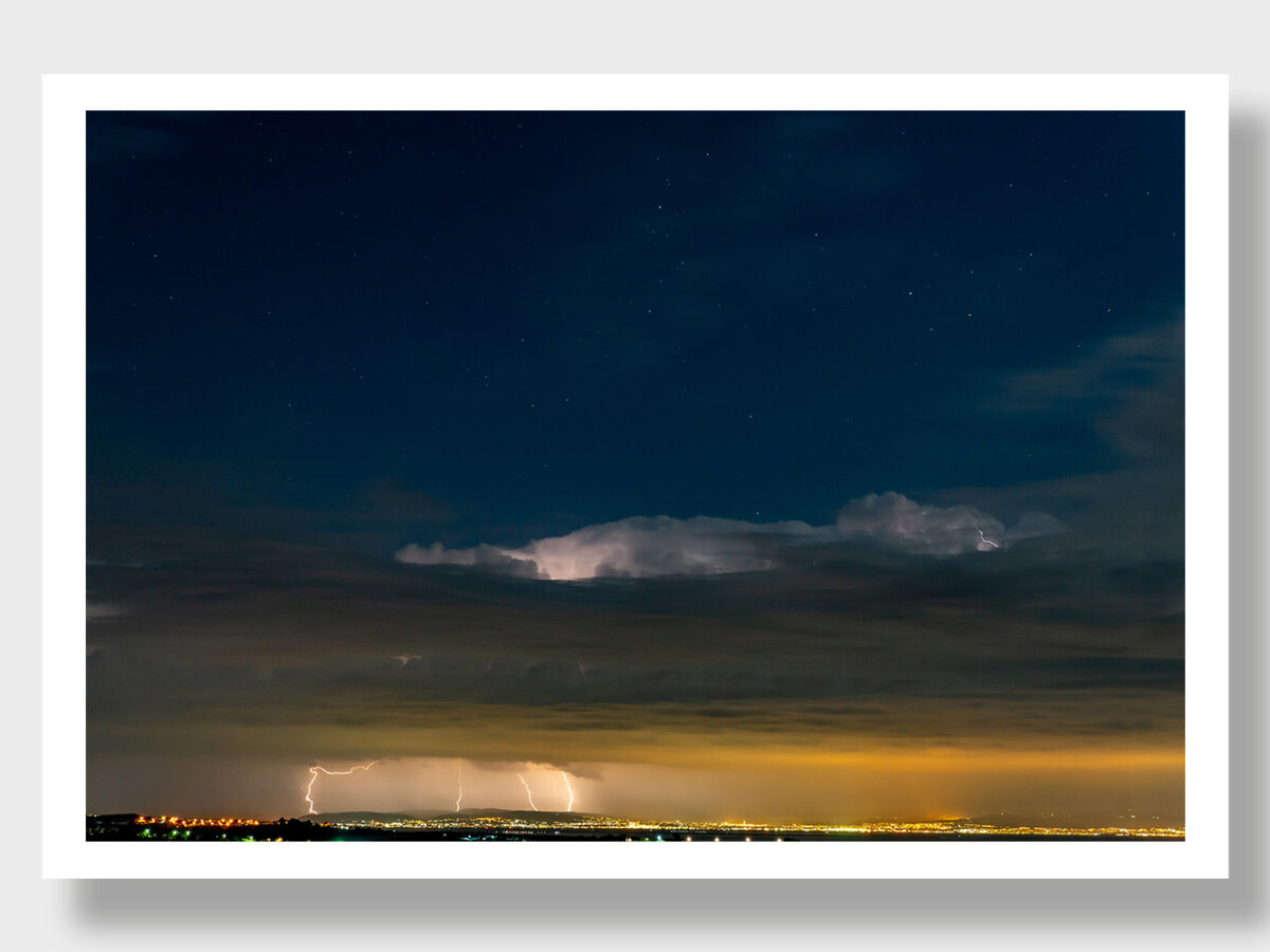 A panoramic view from Greece towards Thessaloniki and Chalkidiki - a dramatic seascape with storm clouds, lightning, and a clear starry sky.