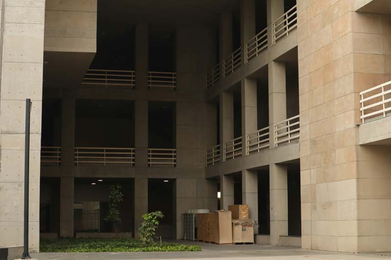 Modern multi‑level concrete building with geometric openings and beige‑gray facade